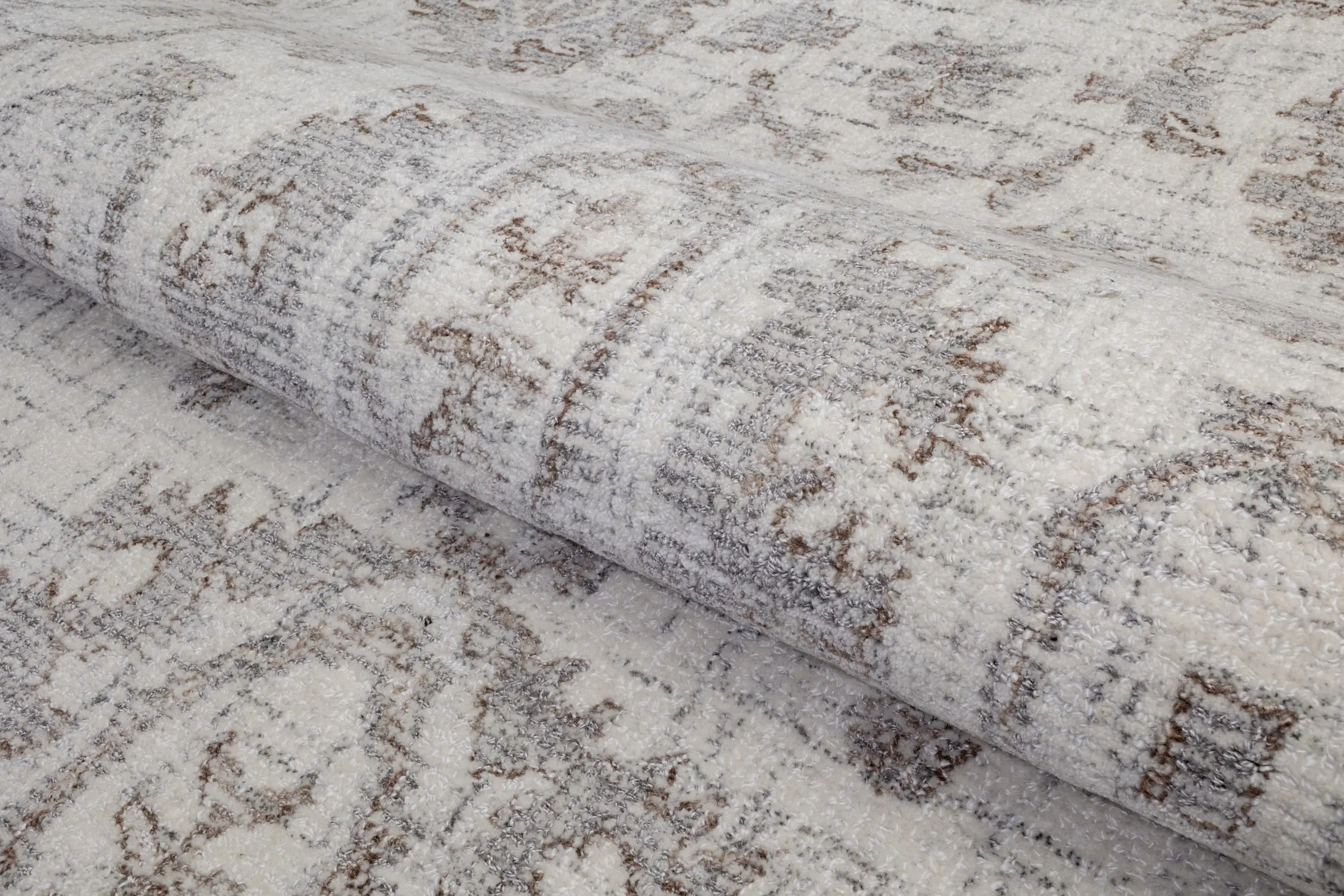 Close-up of a light-colored shag rug with white and brown patterns.