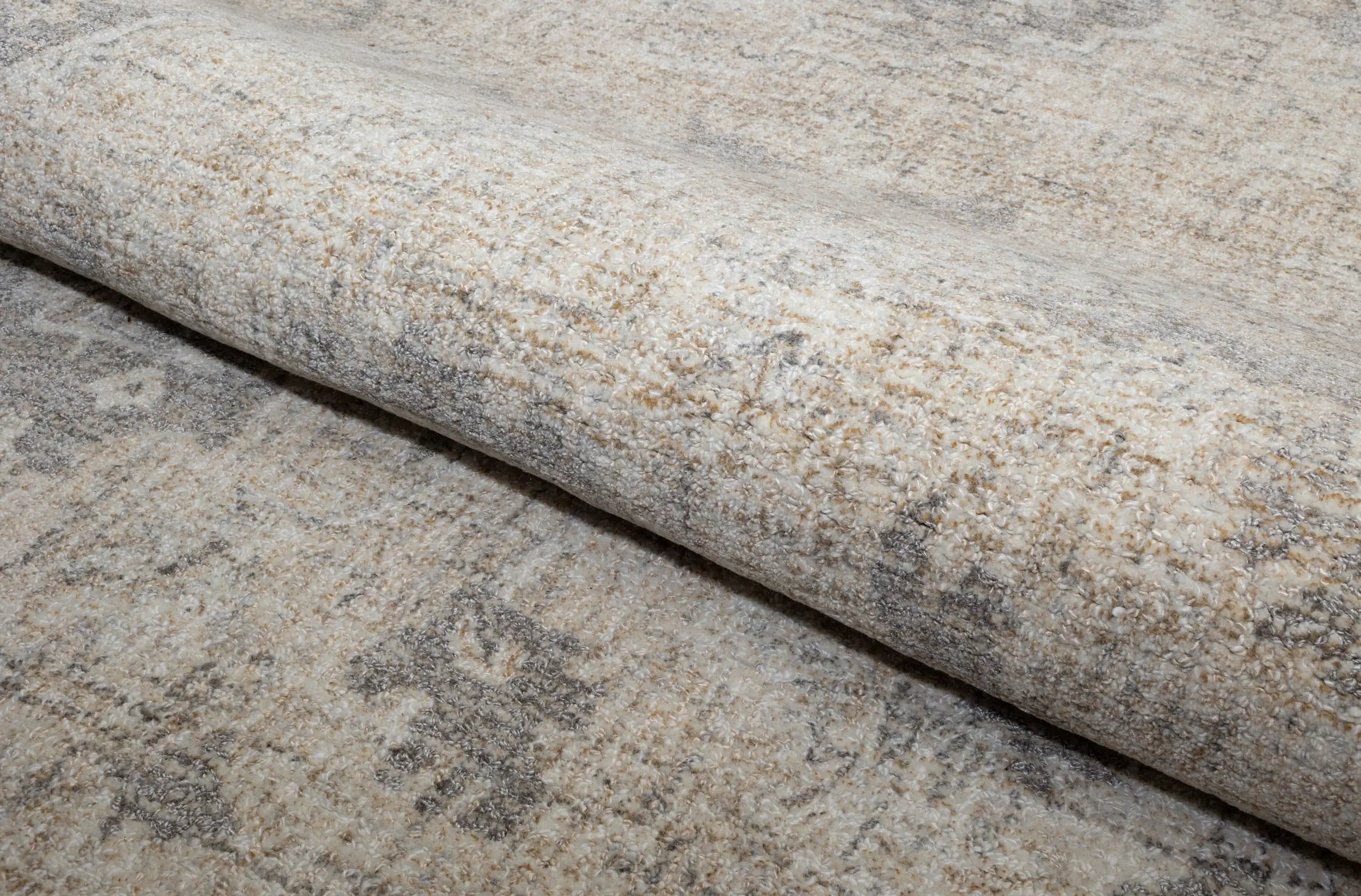 Close-up of a beige and gray textured carpet or rug that's rolled up.