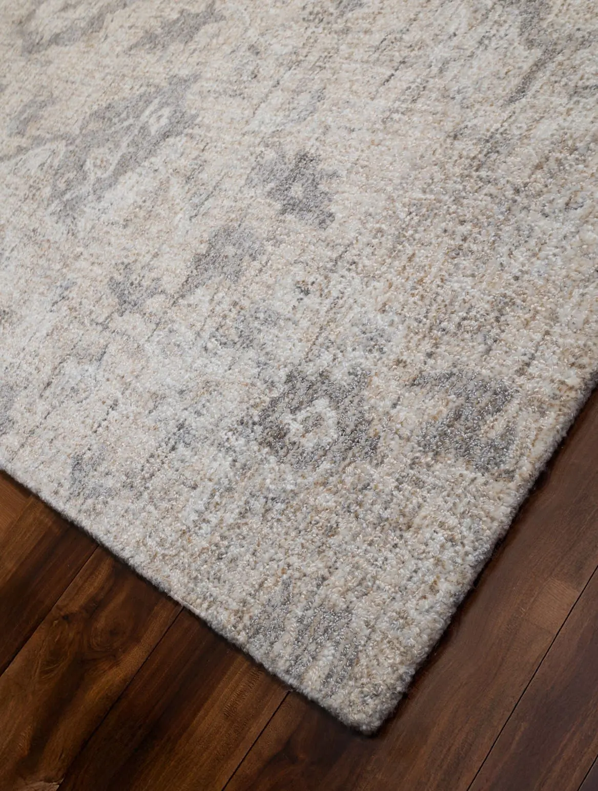Beige and gray patterned area rug on a dark wooden floor