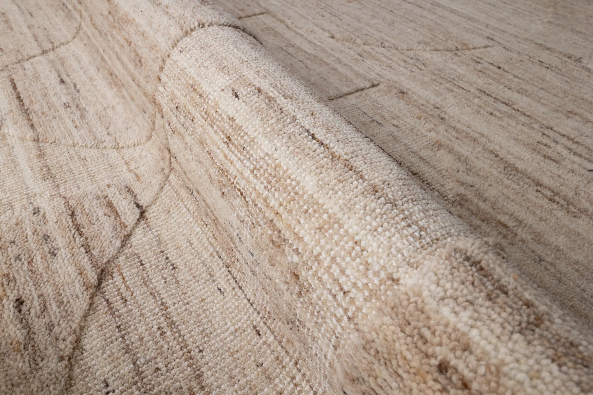Close-up of a beige textured carpet with looped fibers and subtle patterning.